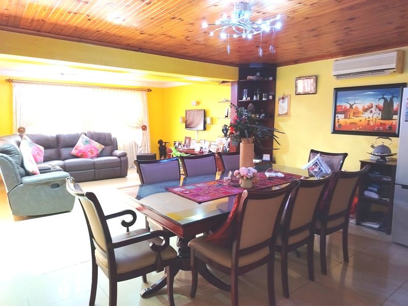 Spacious open-plan living and dining area featuring a warm timber tongue and groove ceiling, tiled flooring, and a wall-mounted air conditioning unit.