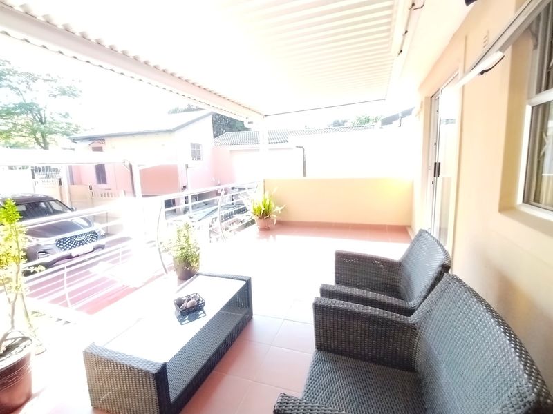 A covered outdoor patio featuring tiled flooring, a metal balustrade, and direct access to the interior through a sliding glass door.