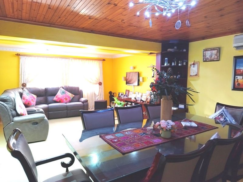 Open plan living and dining area featuring a timber tongue and groove ceiling, built-in shelving, and an air conditioning unit.