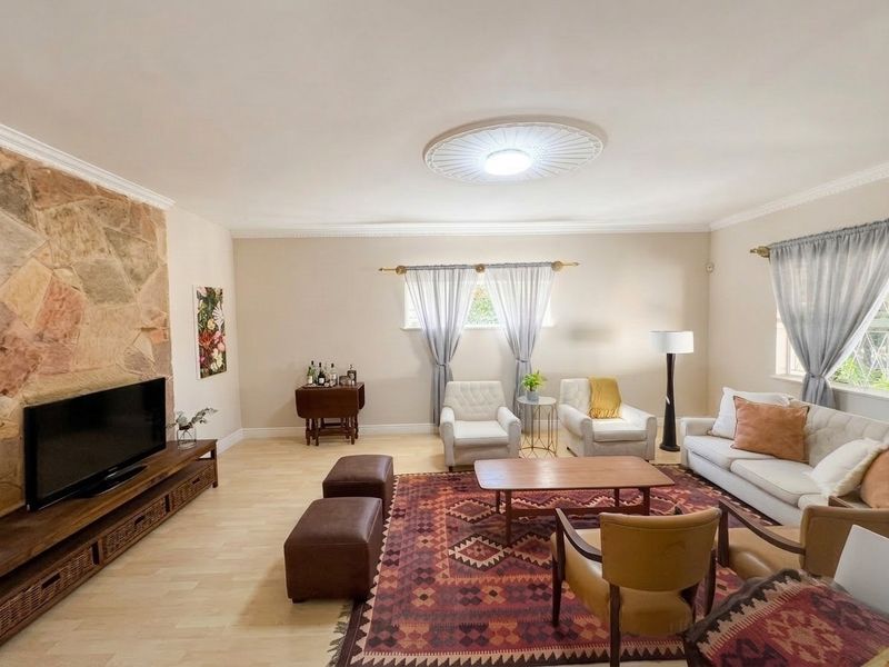 Spacious living room featuring a prominent stone accent wall, crown molding, and a decorative ceiling rose, creating a warm and inviting atmosphere.