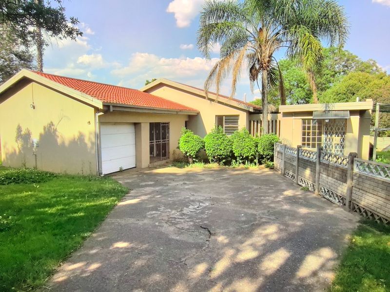 Front exterior view of a single-story house featuring a tiled roof, concrete driveway, garage, and perimeter boundary walling.