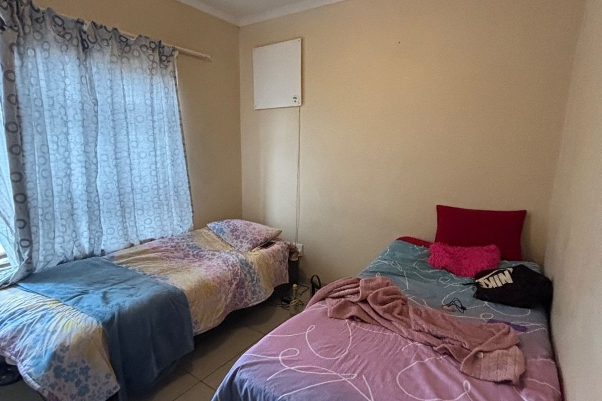 A functional bedroom featuring tiled flooring and a ceiling fan, providing a comfortable space with natural light from the window.
