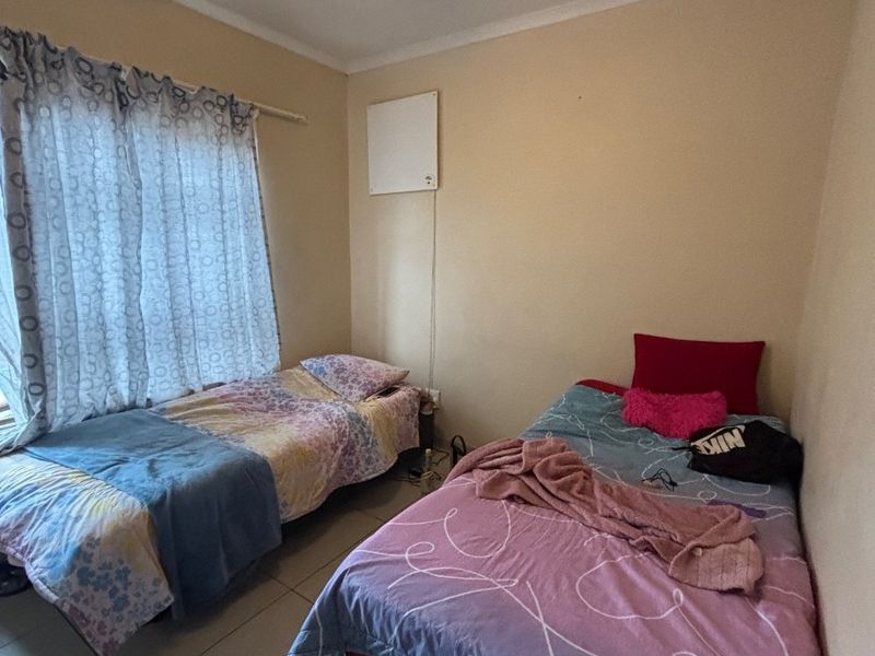 A functional bedroom featuring tiled flooring and a ceiling fan, providing a comfortable space with natural light from the window.
