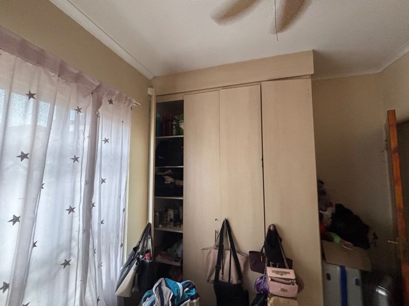 Bedroom featuring built-in cupboards and a ceiling fan, offering functional storage space with potential for cosmetic updates.