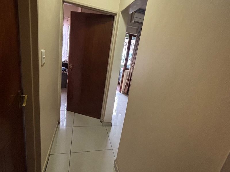 A functional hallway featuring tiled flooring and neutral wall finishes, providing access to adjacent rooms within the apartment.
