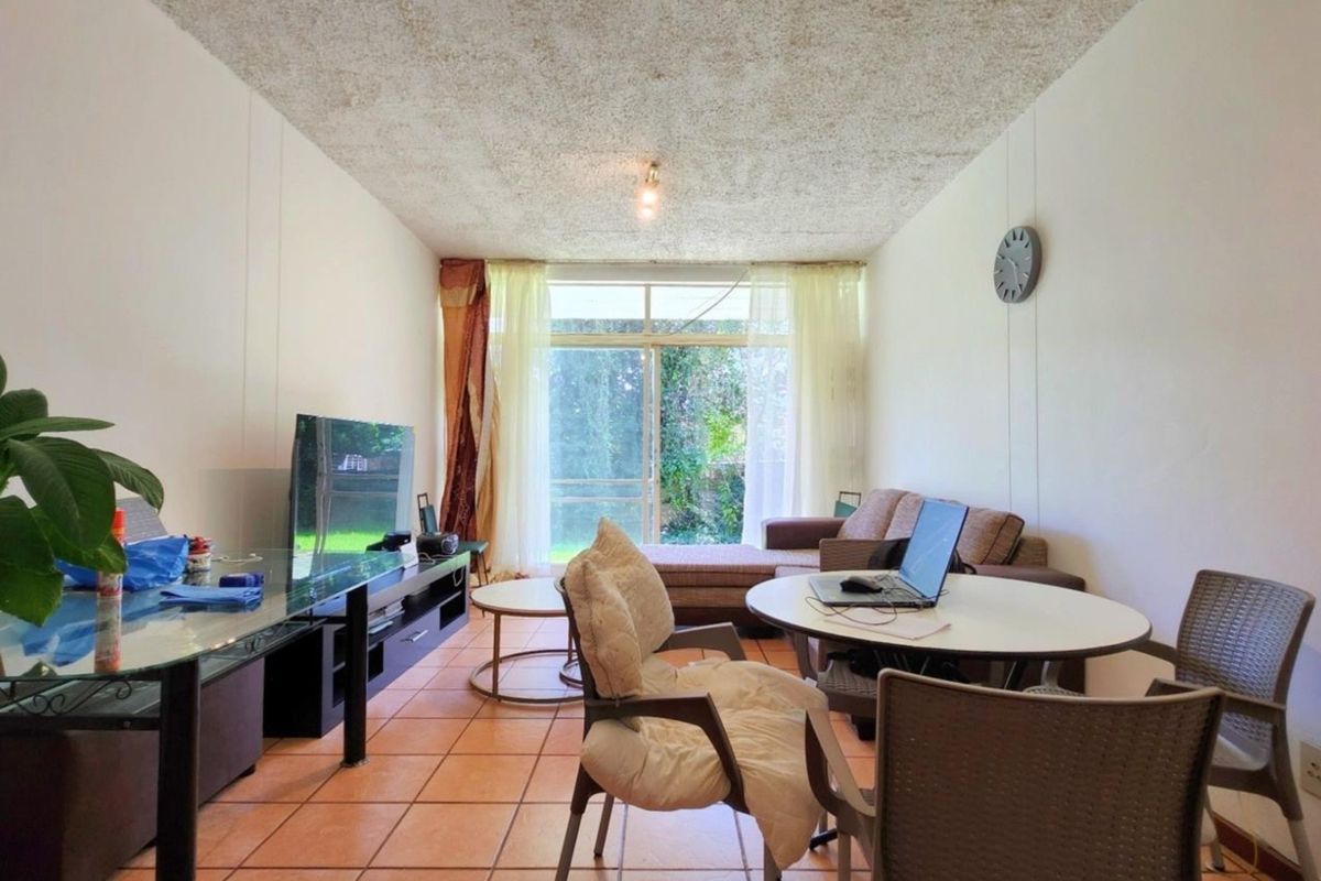 A living room featuring terracotta floor tiles, a textured ceiling, and a sliding glass door providing access to the exterior.