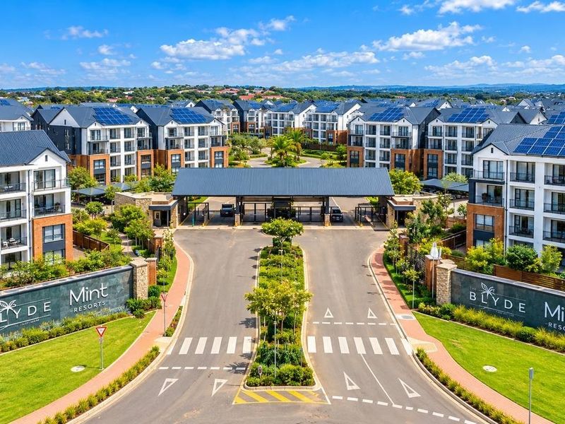 Aerial view of the main entrance and security gatehouse of The Blyde Mint Resorts, featuring modern apartment blocks with solar panels and landscaped grounds.