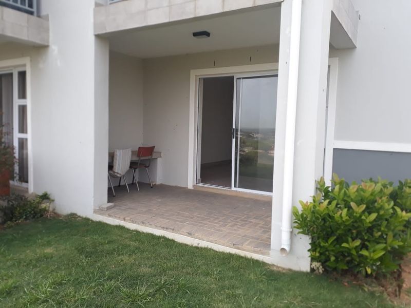 A covered ground-floor patio featuring paved flooring and a sliding glass door providing access to the interior living space.