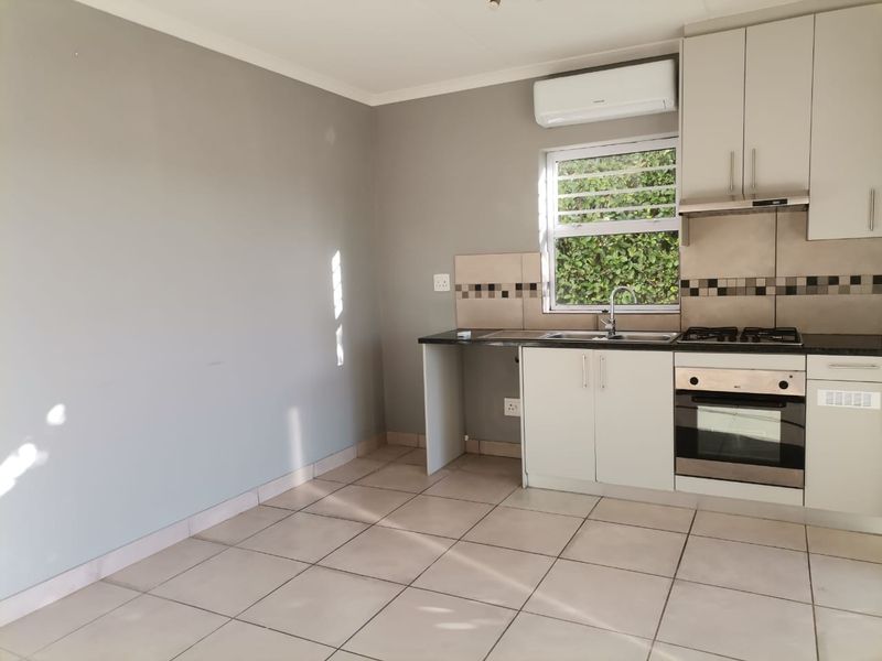 A functional kitchen featuring built-in cabinetry, a gas hob, an oven, and tiled flooring, offering a clean and practical space for culinary activities.