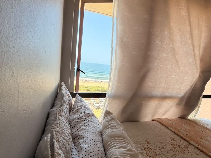 A bedroom featuring a casement window with a direct view of the ocean and beach.
