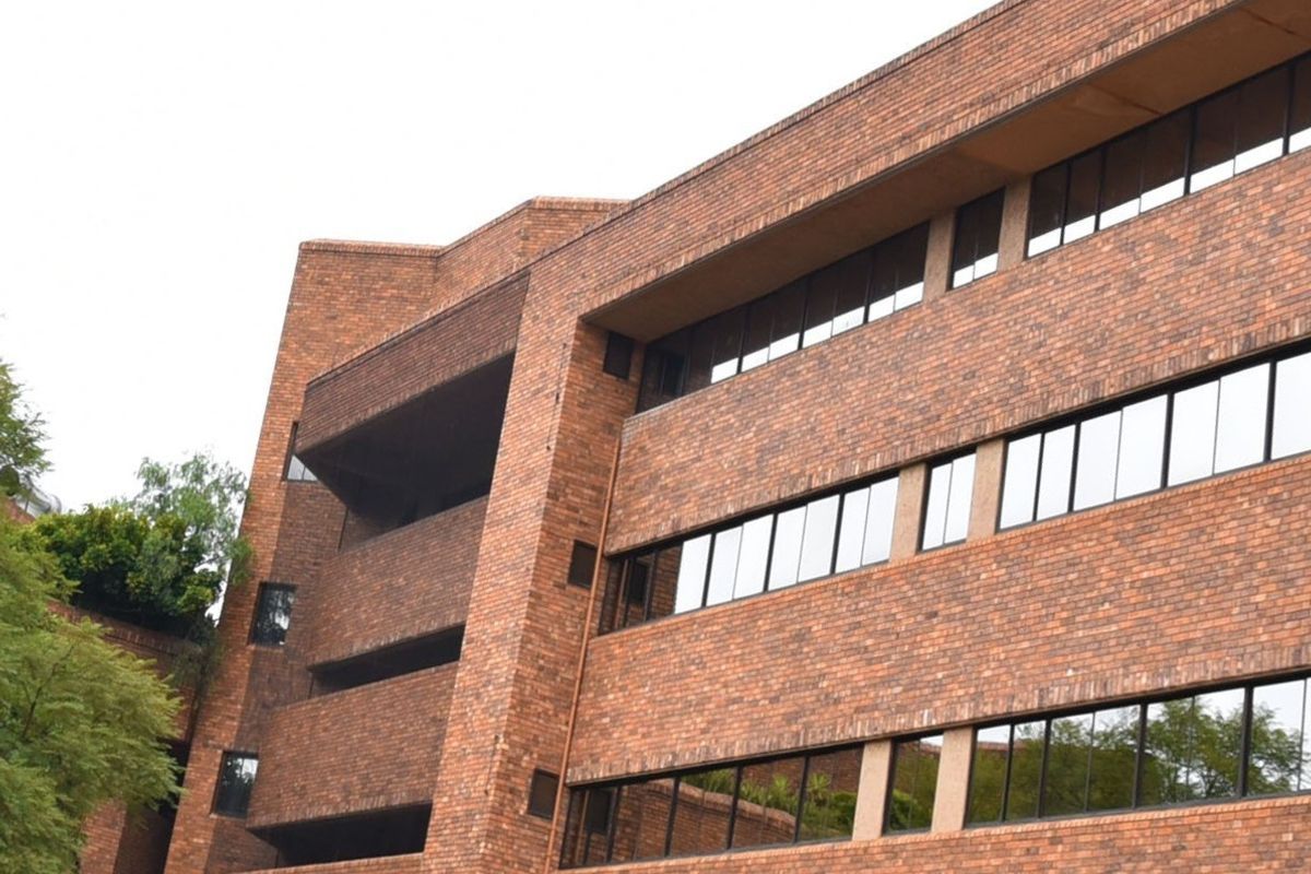 A multi-story commercial building featuring a classic red brick facade with integrated balconies and large, horizontal glass window panels.
