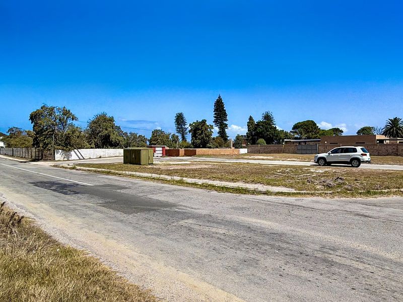 A vacant residential corner plot featuring street access and existing boundary walls, offering a clear site for future development.
