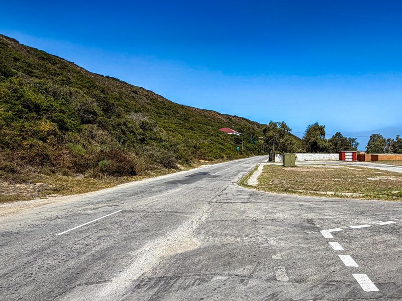 A view of the asphalt road and surrounding landscape, showing the street access and verge area of the property.
