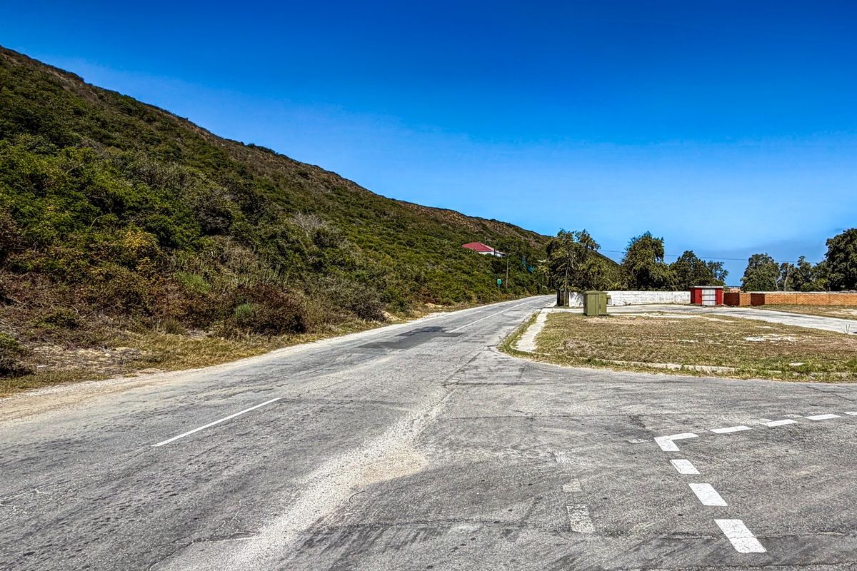 A view of the asphalt road and surrounding landscape, showing the street access and verge area of the property.