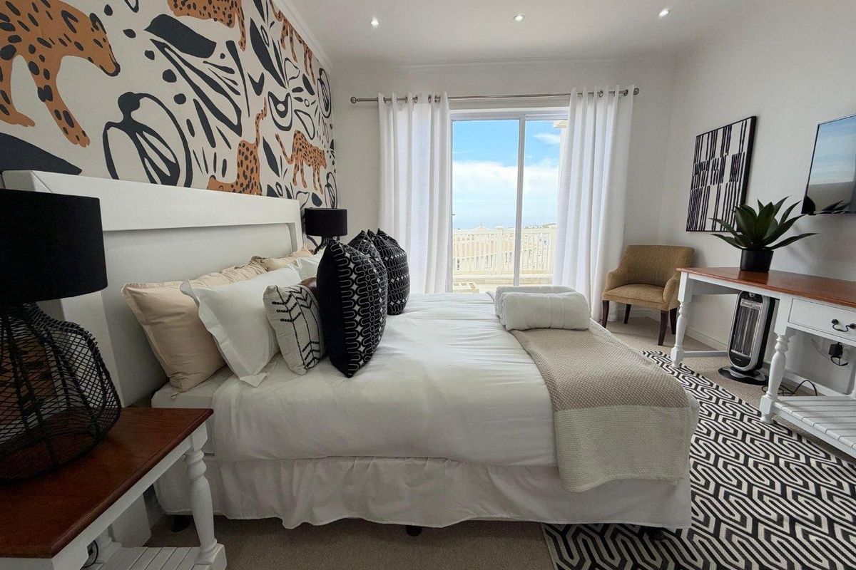 A well-maintained bedroom featuring recessed lighting, carpeted floors, and a sliding glass door providing access to an outdoor balcony with scenic views.