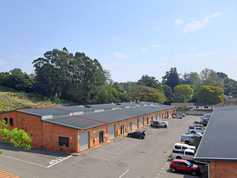Aerial view of an industrial complex featuring brick construction, metal roofing, and dedicated roller shutter access points with an adjacent asphalt parking lot.