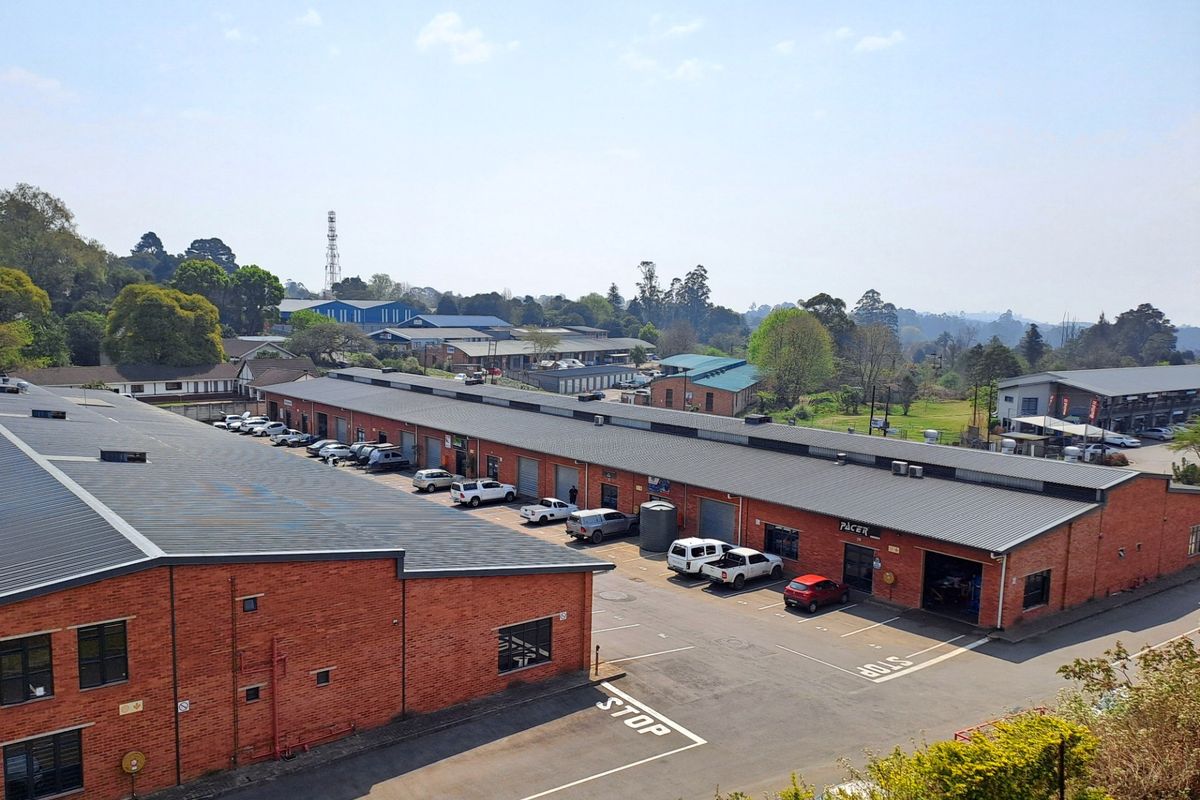 Aerial view of an industrial complex featuring multiple brick warehouse units with corrugated metal roofs and dedicated asphalt parking areas.