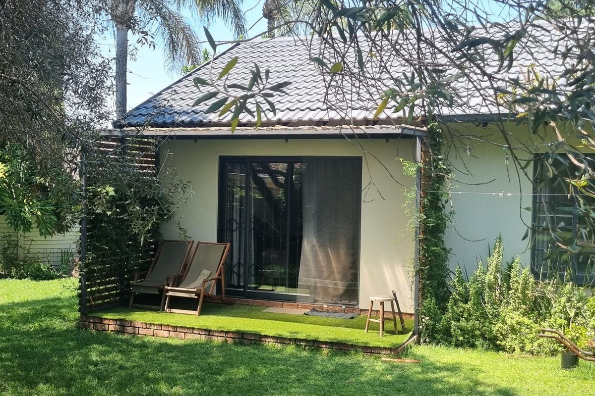 Rear view of the property featuring a covered patio area with artificial turf, brick edging, and a sliding glass door with security gate.