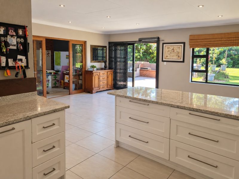Spacious open-plan kitchen area featuring granite countertops, white shaker-style cabinetry, and large sliding doors providing seamless access to the outdoor patio and garden.