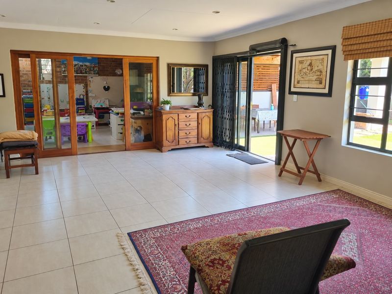 Spacious living area featuring neutral tiled flooring, recessed lighting, and large sliding glass doors providing seamless access to the outdoor patio area.