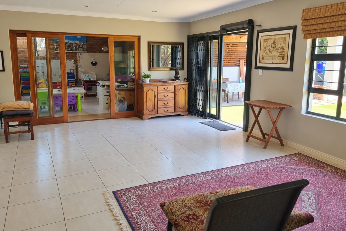 Spacious living area featuring neutral tiled flooring, recessed lighting, and large sliding glass doors providing seamless access to the outdoor patio area.
