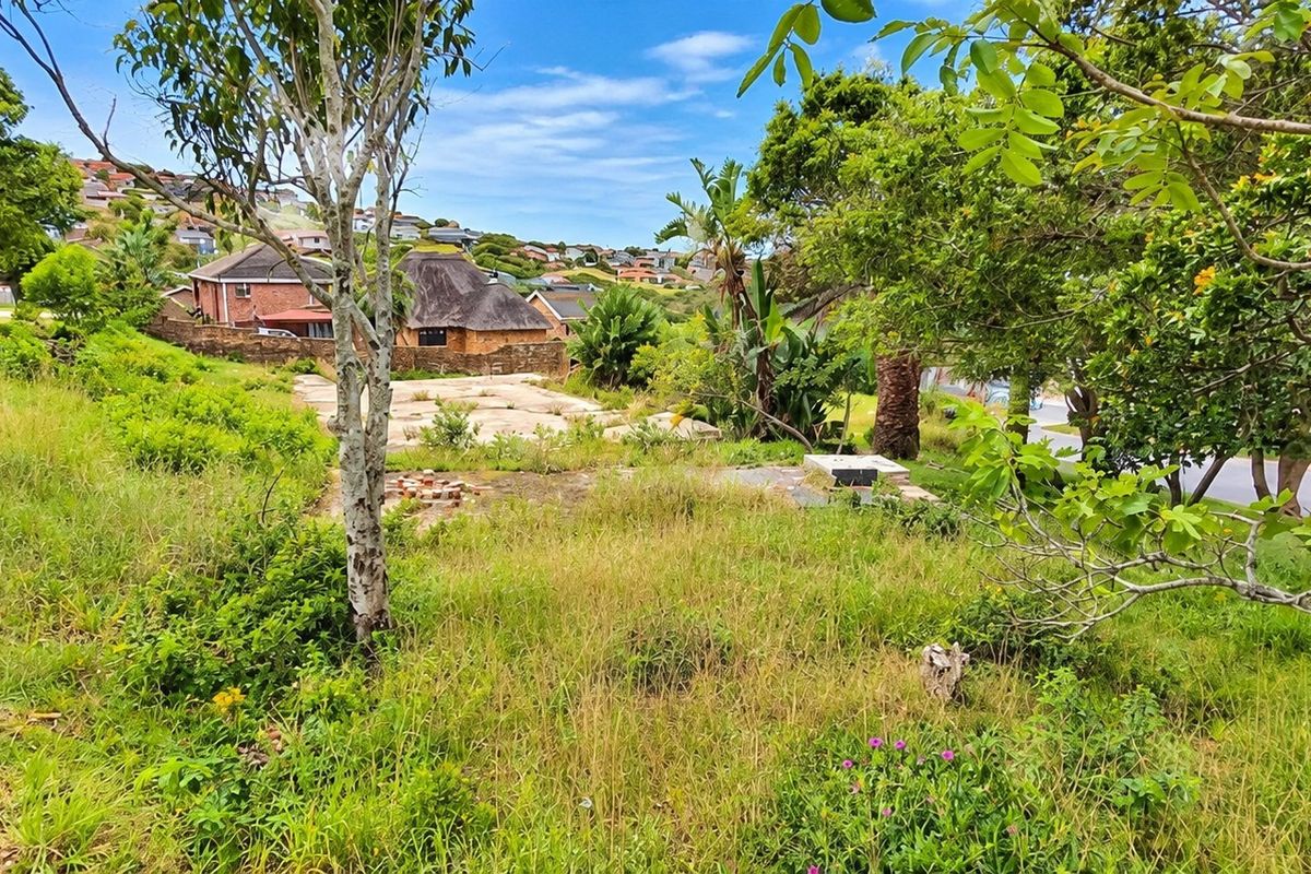 A vacant residential plot featuring an existing concrete slab foundation, surrounded by mature trees and established vegetation in a suburban neighborhood setting.