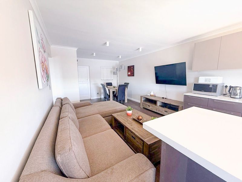 An open-plan living and dining area featuring a modern kitchen with sleek cabinetry and stone countertops, creating a functional and cohesive living space.