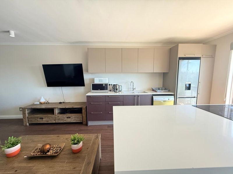 Modern open-plan living area featuring a sleek kitchen with integrated appliances, stone countertops, and durable laminate flooring, seamlessly connecting to the living space.