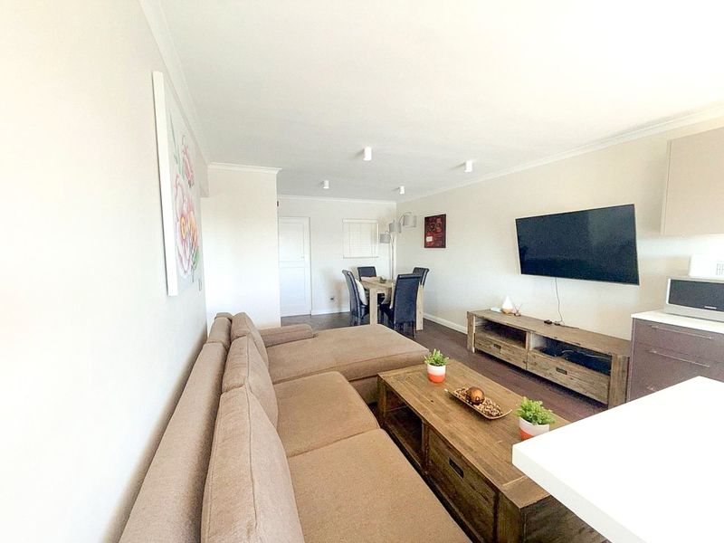 An open-plan living and dining area featuring neutral walls, recessed ceiling lighting, and a functional layout suitable for modern apartment living.