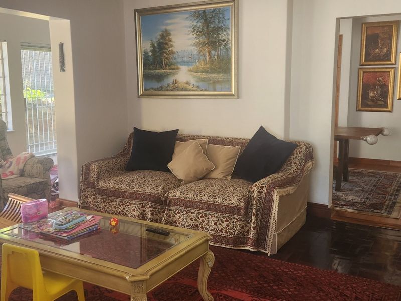 A spacious living room featuring laminate flooring, a stone-clad feature wall, and an air conditioning unit, with natural light flowing from large windows.