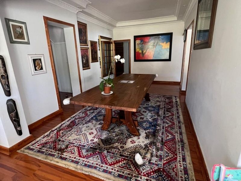 A formal dining area featuring polished hardwood flooring, decorative crown molding, and recessed ceiling lighting.
