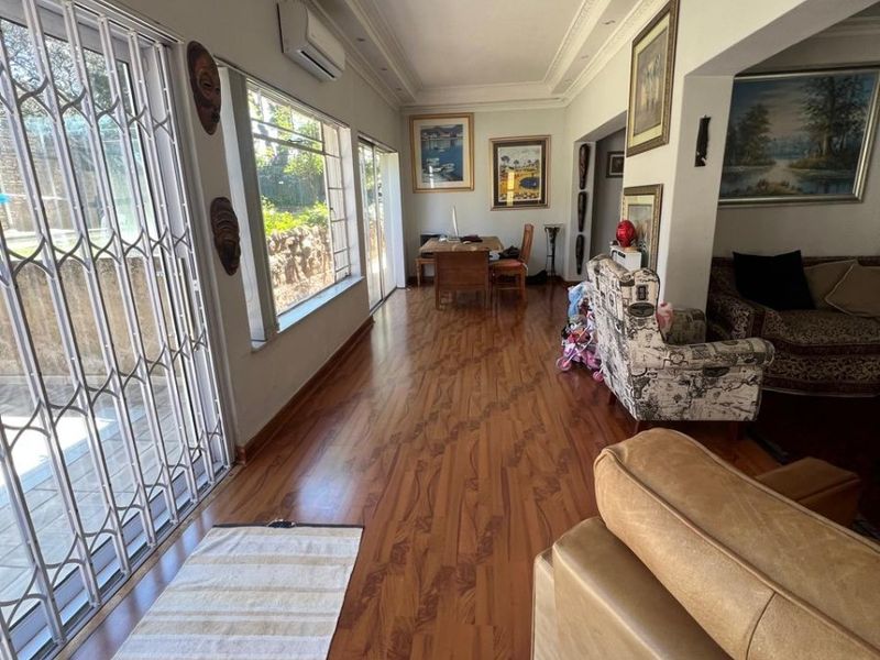 Spacious living area featuring laminate flooring, recessed lighting, ceiling coving, and large windows with security gates, providing access to the outdoor area.