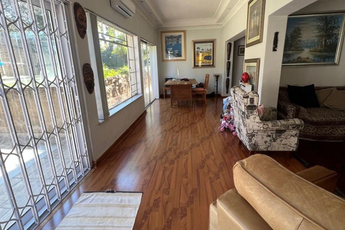 Spacious living area featuring laminate flooring, recessed lighting, ceiling coving, and large windows with security gates, providing access to the outdoor area.