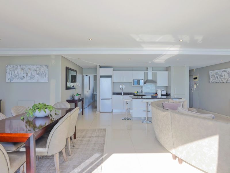 Spacious open-plan living area featuring a modern kitchen with built-in cabinetry, a central island, and sleek tiled flooring throughout.
