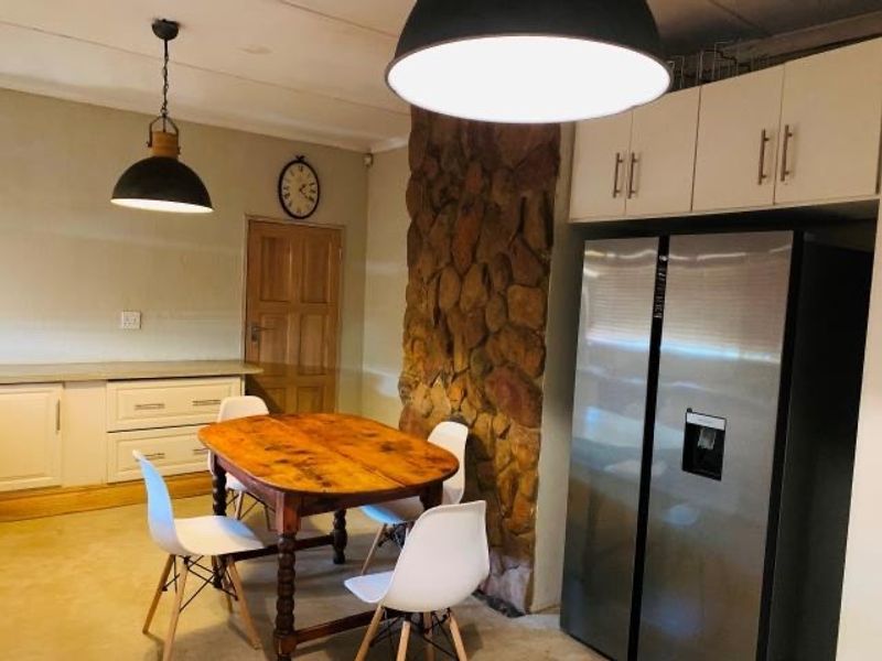 Open plan dining area featuring a rustic stone feature wall, built-in cabinetry, and modern pendant lighting.