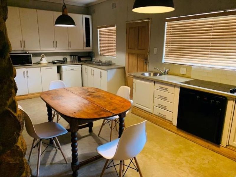 A functional kitchen featuring built-in cabinetry, a tiled backsplash, integrated sink, and built-in oven, with a dining area integrated into the space.