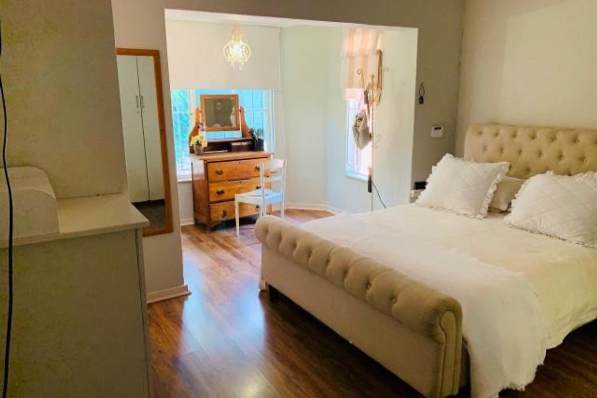 Spacious bedroom featuring laminate flooring, a built-in cupboard, and a bright recessed window area providing natural light.