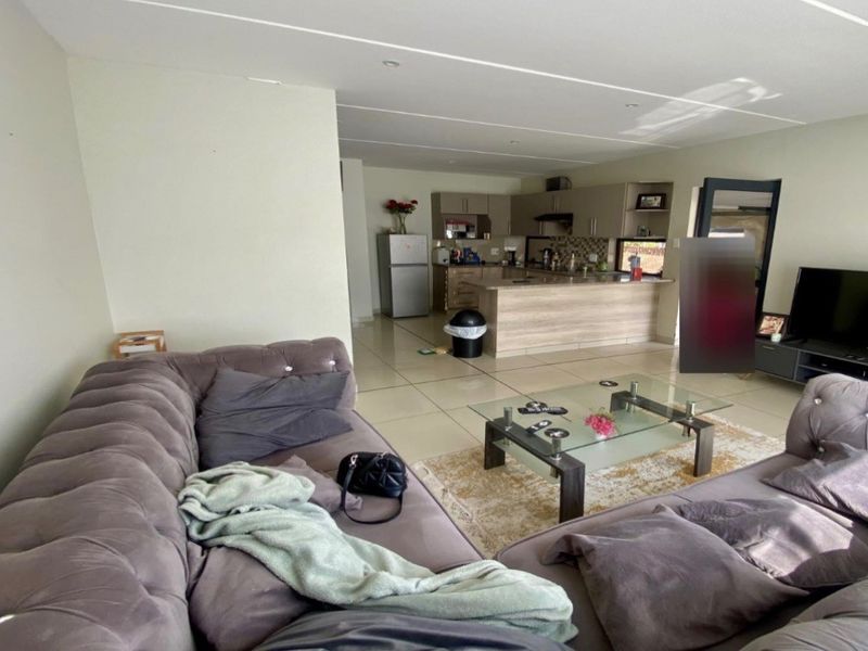 Open-plan living area featuring a modern kitchen with island, tiled flooring, and recessed lighting, creating a functional and connected space for daily living.
