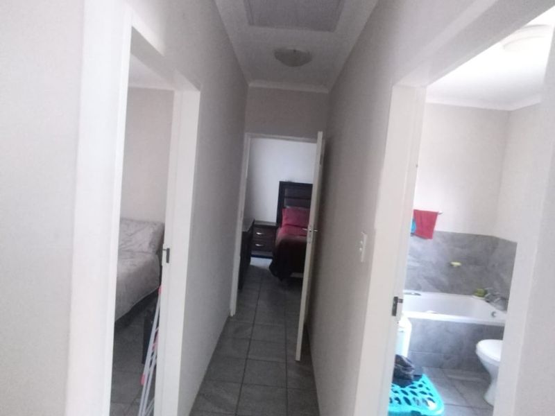 A central hallway with tiled flooring providing access to adjacent bedrooms and a bathroom.