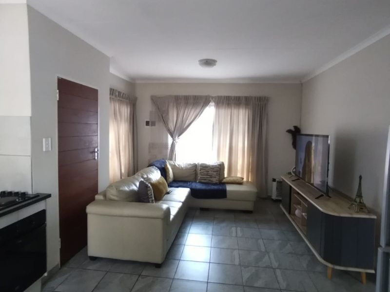 Open plan living area featuring tiled flooring and a compact kitchen corner with built-in oven and hob.