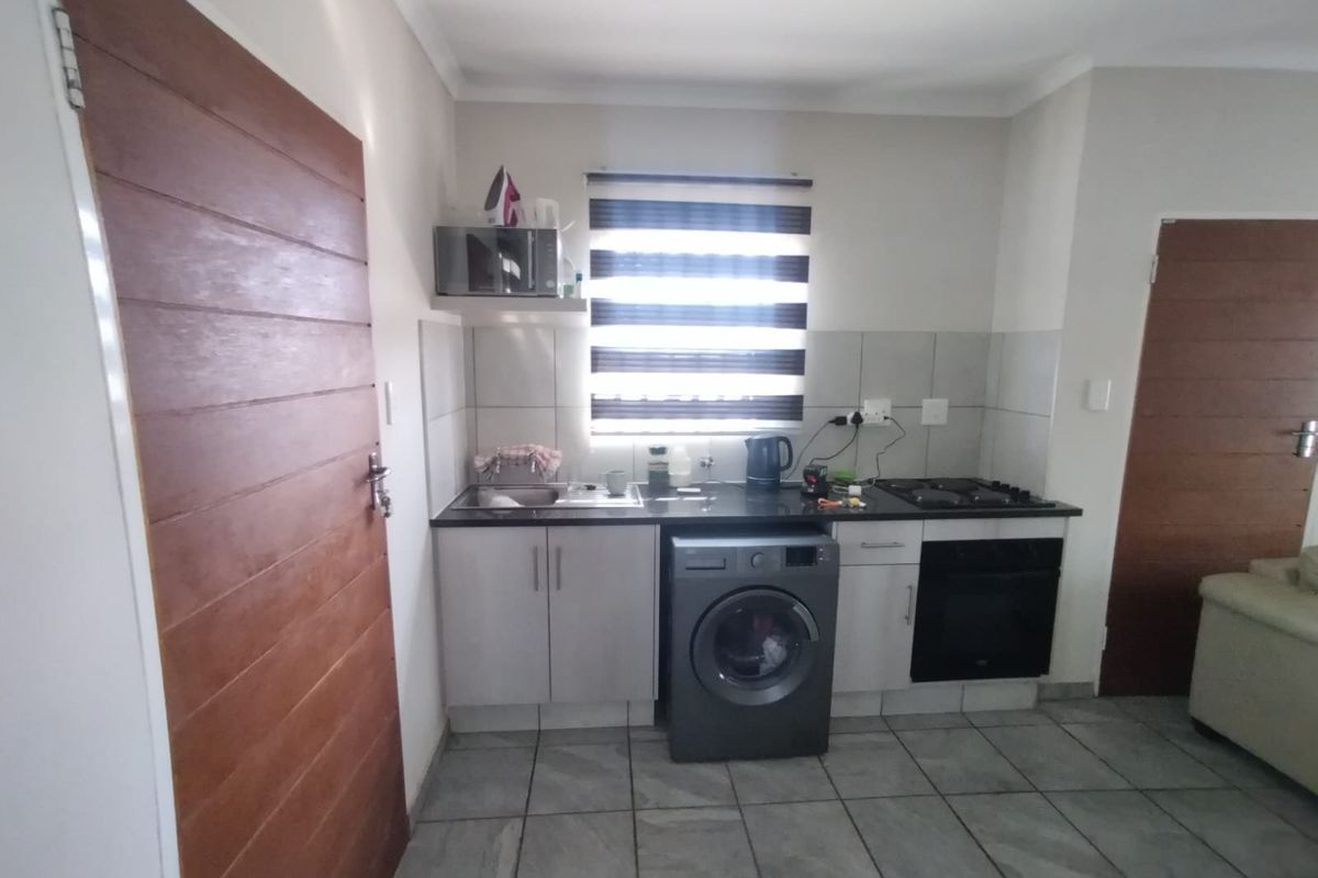 Compact kitchen featuring built-in cabinetry, gas hob, oven, and tiled finishes, providing a functional workspace with integrated laundry appliance space.