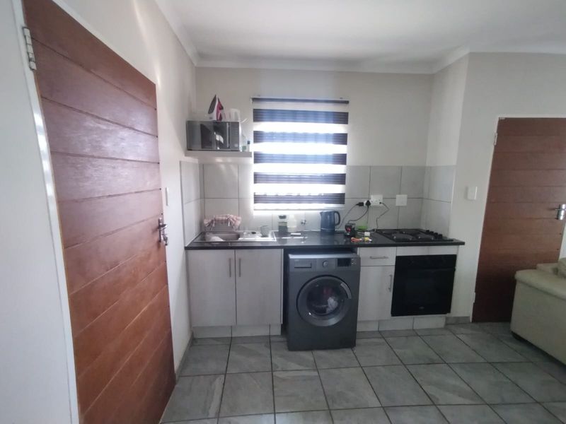 Compact kitchen featuring built-in cabinetry, gas hob, oven, and tiled finishes, providing a functional workspace with integrated laundry appliance space.