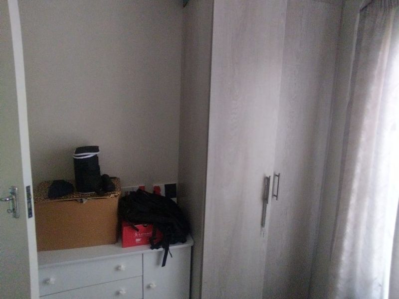 A bedroom featuring a built-in wardrobe and additional built-in cabinetry, providing functional storage space with tiled flooring.