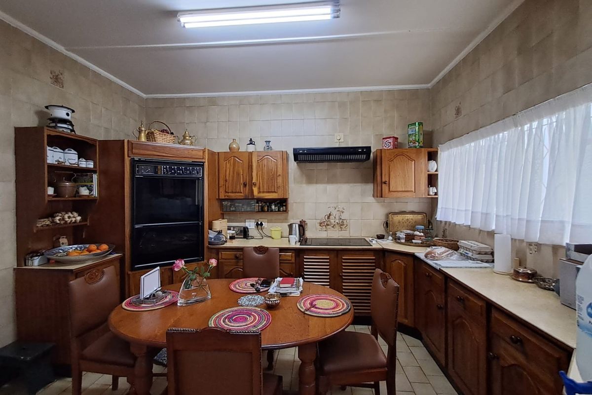 A traditional kitchen featuring wooden cabinetry, a built-in double oven, extractor fan, and tiled finishes, offering a functional layout with space for a dining table.