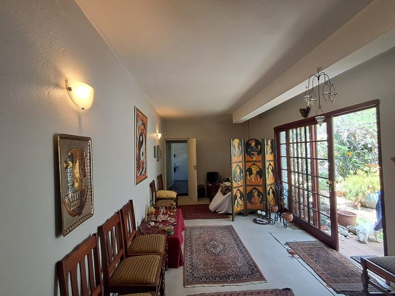 A living area featuring tiled flooring, wall-mounted lighting, and large sliding glass doors that provide direct access to the outdoor garden space.
