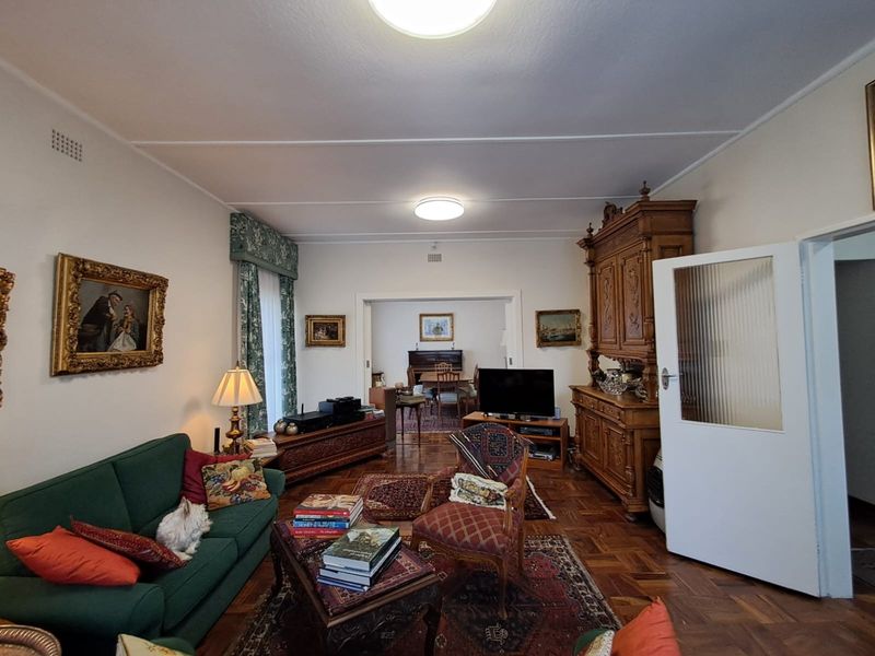 A spacious living room featuring classic parquet flooring and a fluted glass door, offering a traditional aesthetic with potential for modern updates.