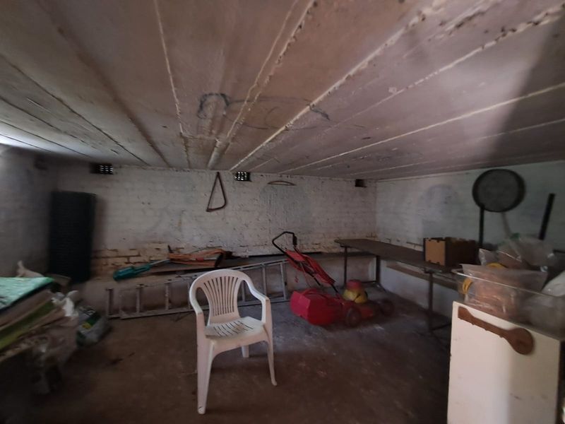 A utilitarian storage or basement space featuring exposed concrete ceilings, painted brick walls, and concrete flooring, suitable for conversion or workshop use.