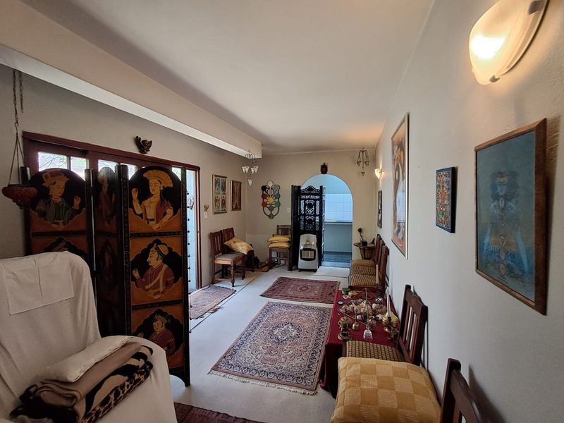 A spacious living area featuring an arched doorway leading to an adjacent room, sliding glass doors, and wall-mounted lighting.