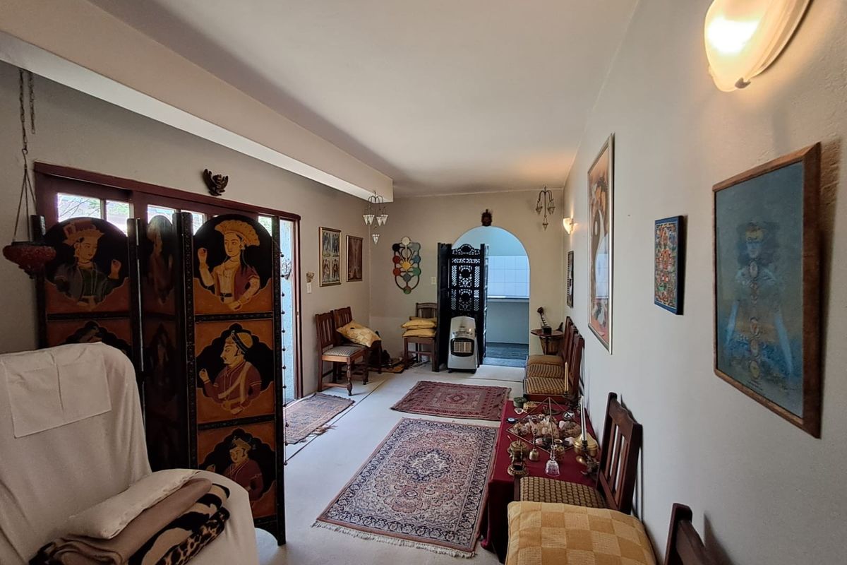 A spacious living area featuring an arched doorway leading to an adjacent room, sliding glass doors, and wall-mounted lighting.