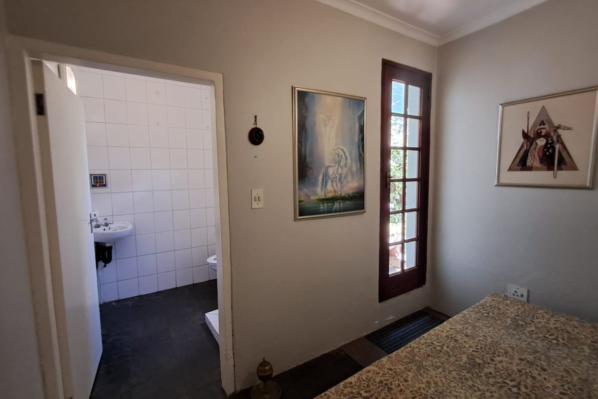 A bedroom featuring an en-suite bathroom with tiled flooring and a glass-paneled door providing access to the exterior.